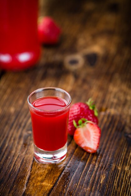 Foto porzione di liquore alla fragola sul fuoco selettivo del fondo di legno