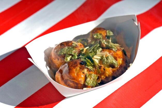 Portion of takoyaki over red and white striped tablecloth