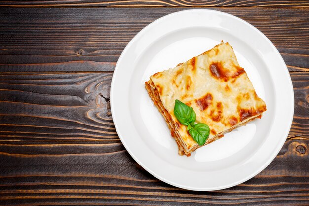 Portion of tasty lasagna on wooden backgound