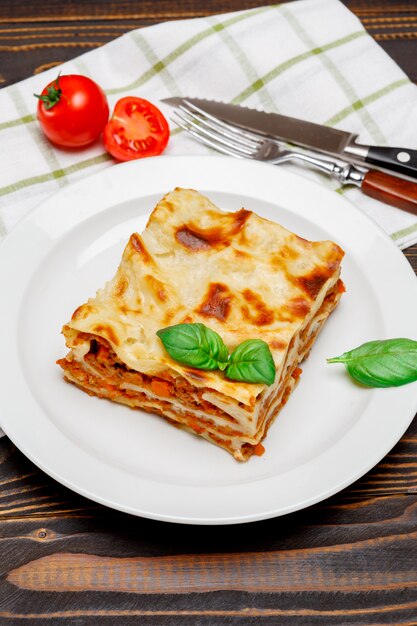 Portion of tasty lasagna on wooden backgound