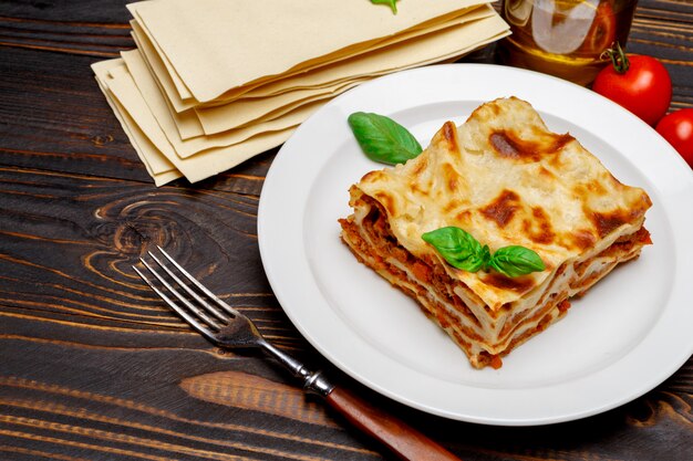 Portion of tasty lasagna on wooden backgound