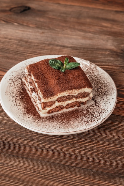 Portion of tiramisu italian dessert on wooden background