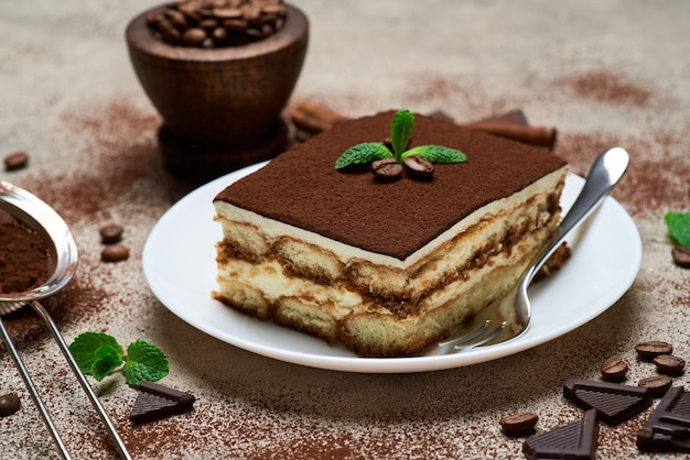 Portion of traditional italian tiramisu dessert on grey concrete table