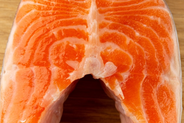 Portion of uncooked red salmon cut in slice and placed on the wooden surface