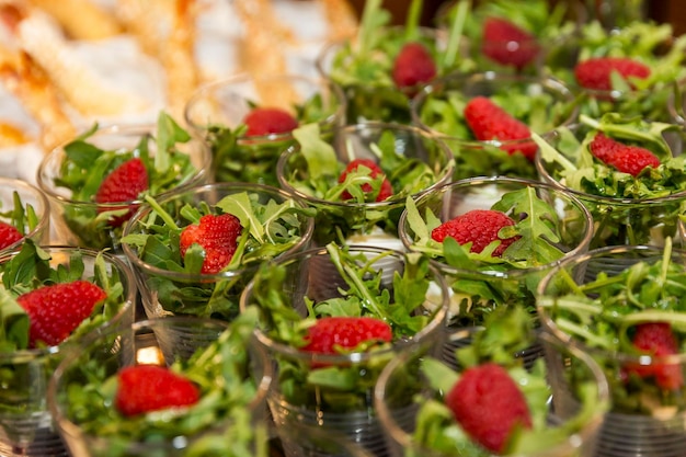 Portioned salads with arugula and raspberries in small glasses on the buffet table Holidays celebrations and business meetings Closeup