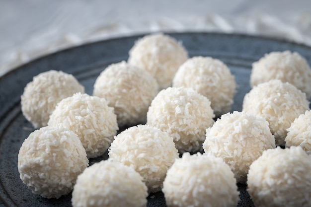 Photo portions of white chocolate coconut candy balls on blue plate, selective focus food