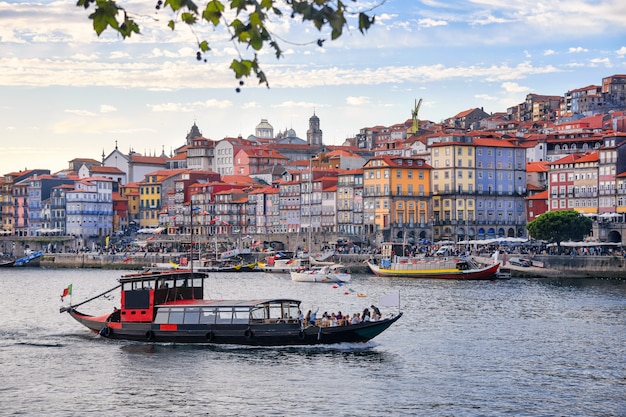 Porto, Portugal old town ribeira aerial promenade view with colorful houses, traditional facades, old multi-colored houses with red roof tiles, Douro river and boats. Aerial cityscape image of Porto