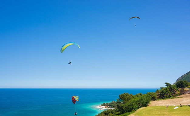 ポルトノヴォイタリア2022年5月8日コネロ自然イタリアの風光明媚な海岸線上空を飛ぶパラグライダー地中海の海の観光地の劇的な海岸岬上空のエクストリームスポーツ