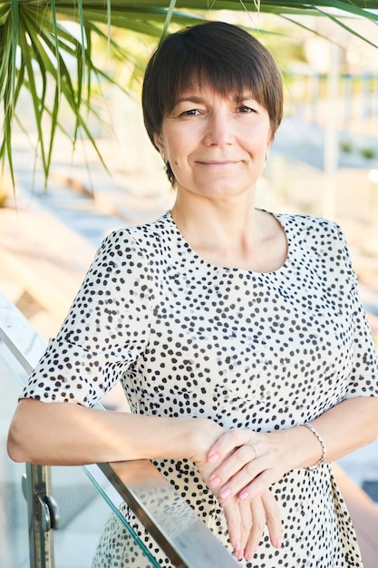 Portrait of 50 year old happy caucasian business woman posing and smiling in the park adult healthy real lady on the background of nature