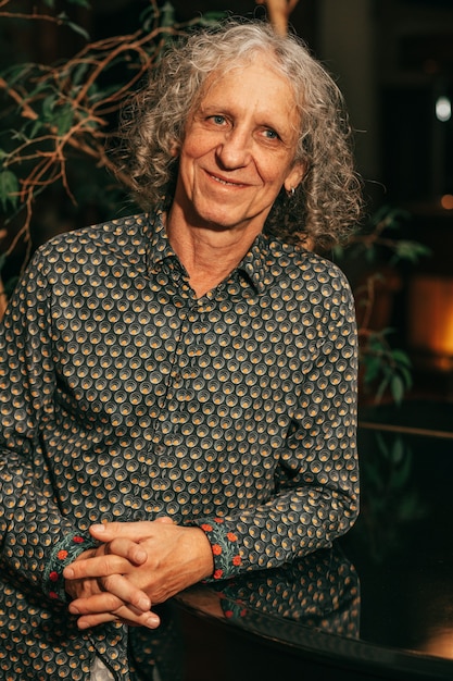 Photo portrait of 65-year-old man with gray curly hair looks away, smiles, profession artist, musician, actor. human body part