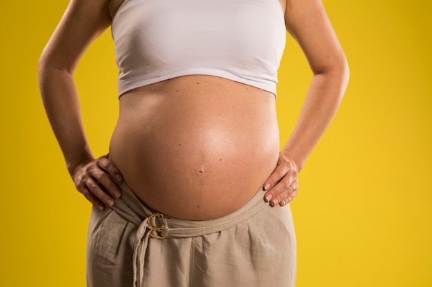 Portrait of 9 months pregnant woman over yellow wall