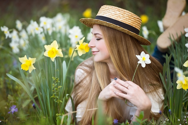 写真 庭の水仙の花と麦わら帽子の美しい女性の肖像画。園芸。