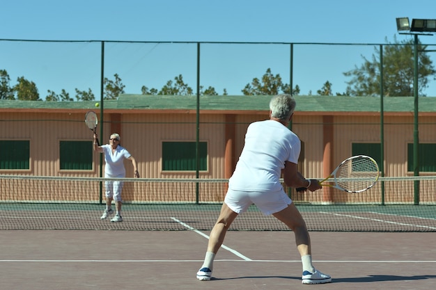 Portrait of active senior couple on tennis court