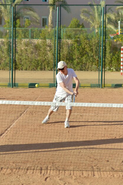 Photo portrait of active senior man playing tennis outdoors