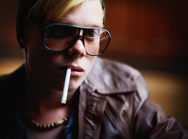 Portrait addiction and a boy smoking a cigarette closeup for nicotine or tobacco dependency in sunglasses Face smoke and bad habit with a young person inhaling an addictive substance for cancer