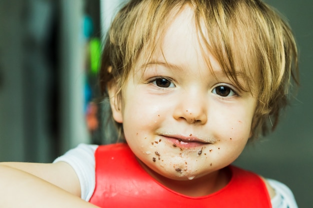 Portrait adorable child eating chocolate sponge cake