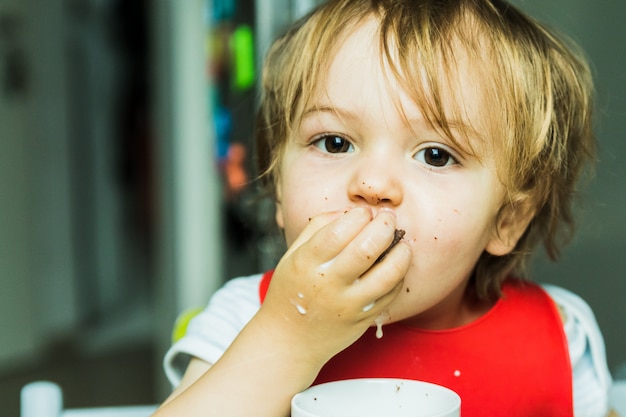 Портрет прелестный ребенок ест шоколадный бисквит