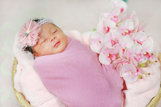 Portrait adorable of little asian newborn baby sleeping on fluffy soft towel in basket