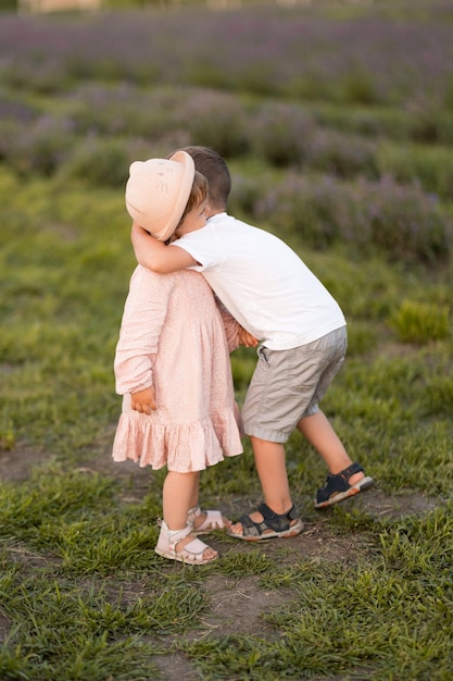 Portrait of adorable little brother and sister walking in the lavender hugging and smiling