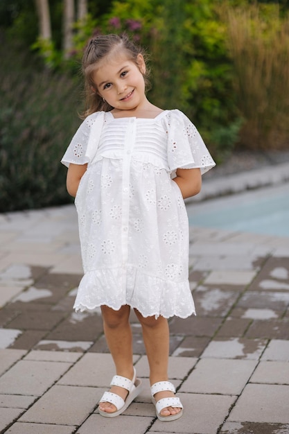 Photo portrait of adorable little girl in beautiful white summer dress five year old girl smile