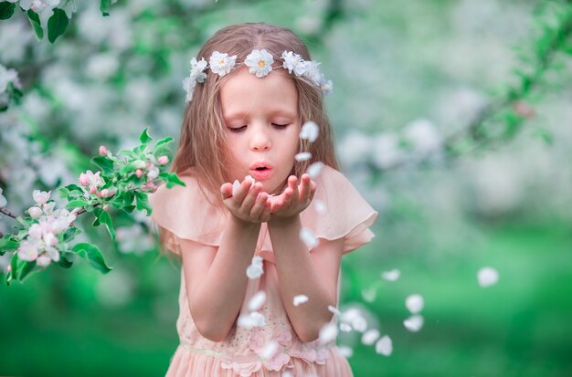 Портрет очаровательны маленькая девочка в цветущий вишневый сад на открытом воздухе