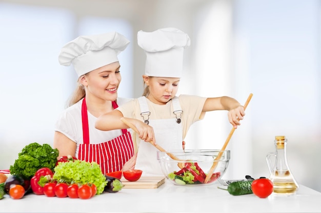 Portrait of adorable little girl and her mother cooking together