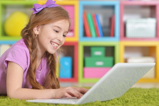 Portrait of adorable little girl using modern laptop