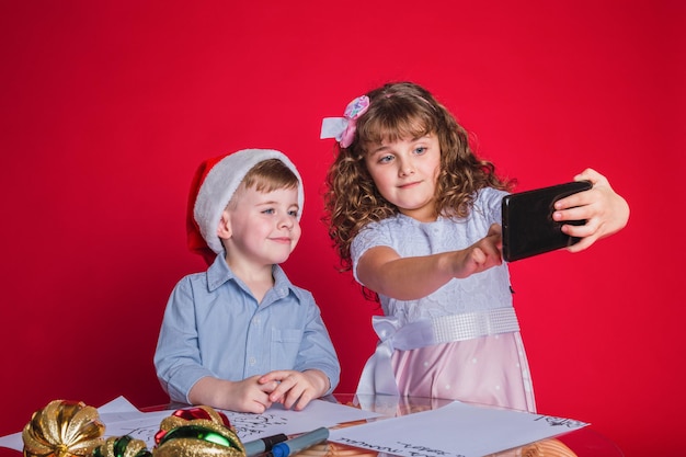Photo portrait of adorable little kids in christmas hats taking a selfie