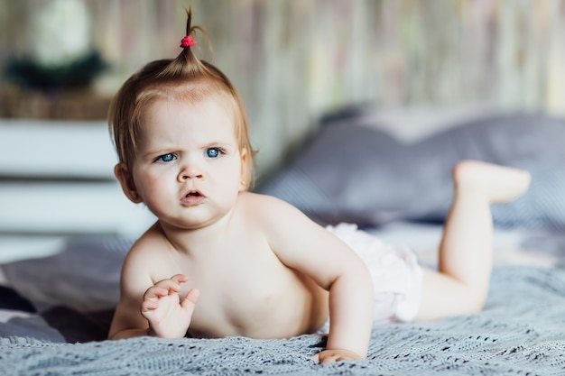 Photo portrait of an adorable littlegirl crawling on the bed with candid emotion