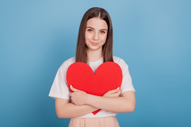 Portrait of adorable sweet lady embrace red heart figure on blue background