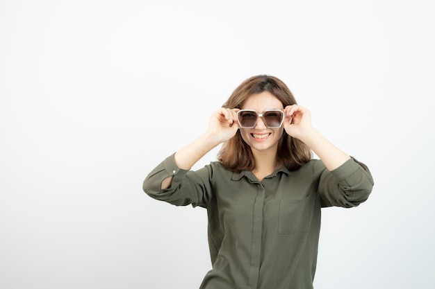 Portrait of adorable young woman in eyeglasses standing over white. High quality photo