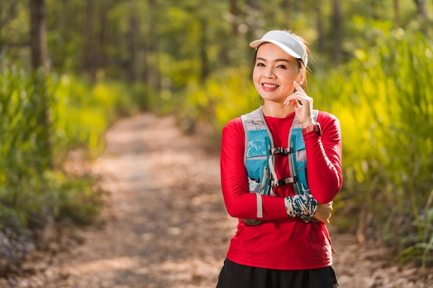 Ritratto di donna asiatica adulta trail runner con gilet da corsa facendo trail running training nel parco forestale