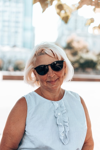 Portrait of adult blonde positive satisfied mature woman in sunglasses smiling