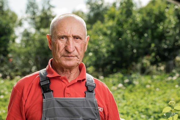 Foto ritratto di un contadino adulto sorridente e guardando la telecamera un allegro vecchio con i capelli grigi che indossa un grembiule all'aperto con una copia dello spazio