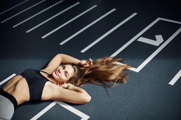 Portrait of adult fitness idol woman laying on gym floor looking at camera smiling Perfect body and soul balance