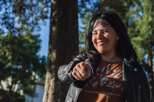 Portrait adult latin woman outdoors smiling and pointing the finger at the camera