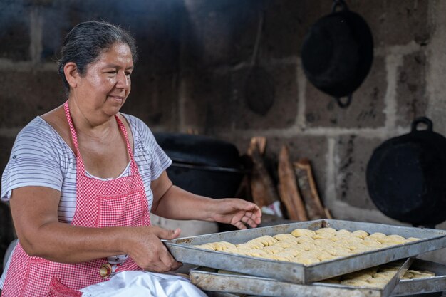 오븐에서 요리할 음식을 많이 준비하는 성인 라틴 여성의 초상화