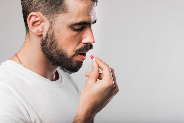 Photo portrait of adult male taking a pill