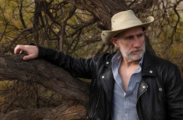 Photo portrait of adult man in cowboy hat against tree