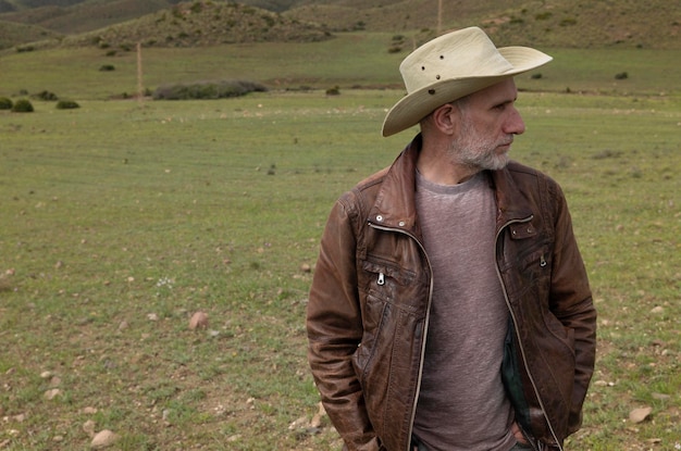 Foto ritratto di un uomo adulto con un cappello da cowboy sul campo