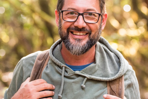 Portrait of adult man smiles and looks at front outdoors