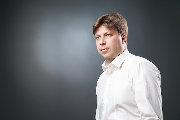 Portrait of adult man in white shirt looking away against of black background