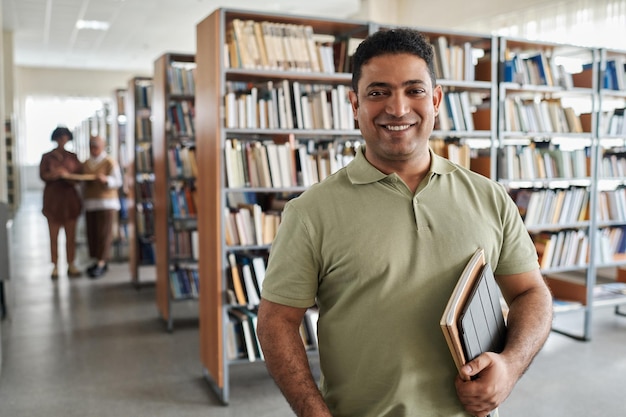 Photo portrait of adult student smiling at camera while standing in the library