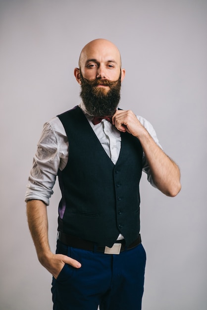 Portrait of an adult stylish bearded man on a grey looking at the camera