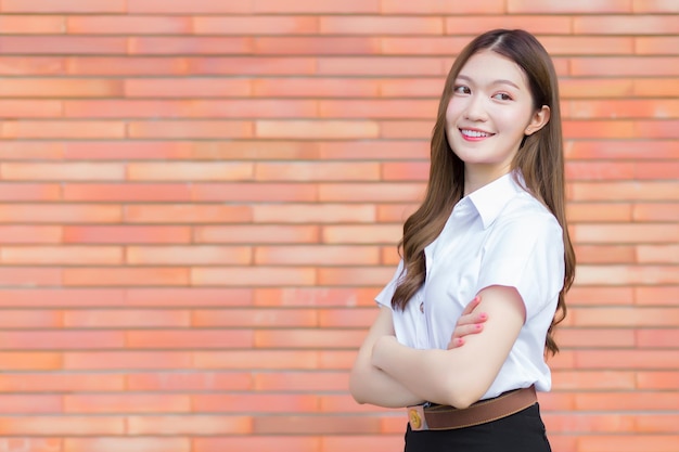 Portrait of adult Thai student in university uniform Asian beautiful girl with her arms crossed