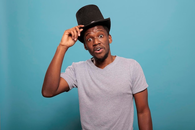 Photo portrait of adult with classic top hat on head in front of camera, doing magical performance with artistic prop costume in studio. person wearing vintage costume topper for fun.