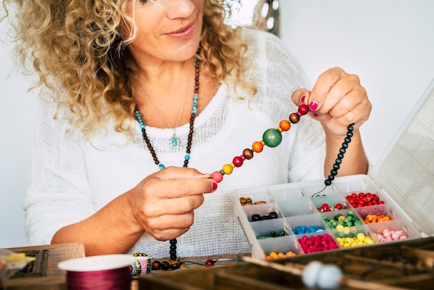 Portrait of adult woman creating beads bracelets and necklace at home for new modern and trendy business