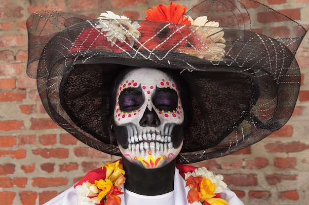 Portrait of an adult woman with her eyes closed wearing La Calavera Catrina makeup and costume