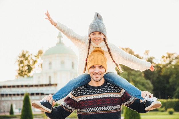 Portrait of affectionate father gives piggy back ride to his daughter