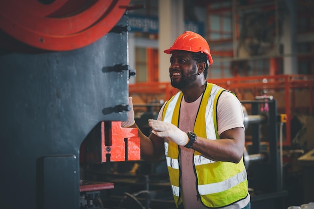 Ritratto afroamericano nero afro lavoratore in fabbrica camerun uomo nero dipendente lavoro in stabilimento di produzione fabbrica industria e linea operatore macchina acciaio metallo utilizzando casco per la sicurezza